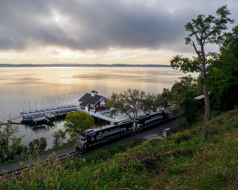 Finger Lakes Railway local passing a lakeside boathouse at dawn